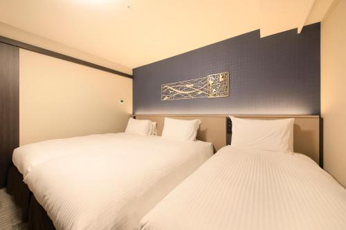 two beds in a room with white sheets at Richmond Hotel Yokohama Ekimae in Yokohama