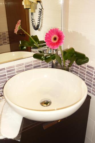 a white sink with a vase with a pink flower at Hotel La Sacca in Stresa