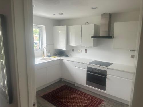 a kitchen with white cabinets and a sink and a stove at Luxe retreat Unwind in Elegant Style in Hatch End