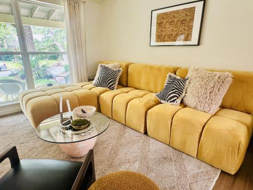Sofá amarillo en la sala de estar con mesa de cristal en The Marigold, en Austin