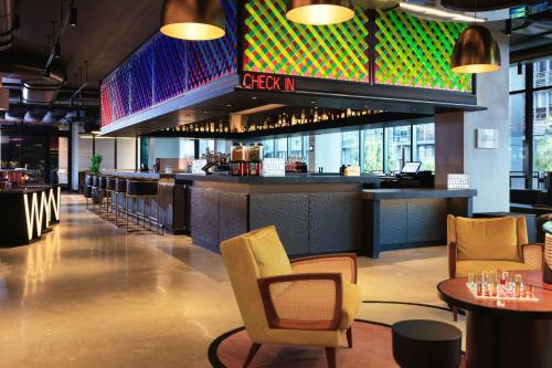 a restaurant with a bar with chairs and tables at Moxy Miami Wynwood in Miami