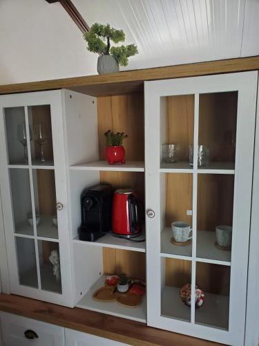 a white cabinet with glass doors in a kitchen at ARCADIA Village in Merei