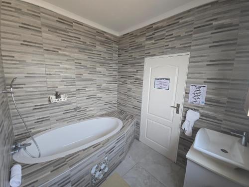 a bathroom with a bath tub and a sink at Tlokweng Rose Garden Guesthouse in Gaborone