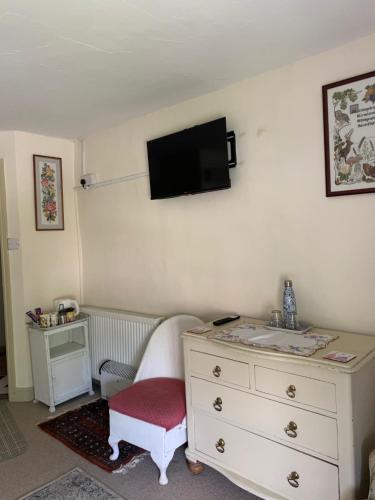 a bedroom with a dresser and a tv on the wall at Manor Farm Bed & Breakfast in Gillamoor