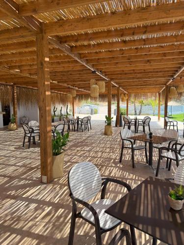 a patio with tables and chairs under a wooden roof at Korineum Golf & Beach Resort in Kérynia