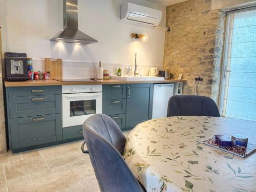 a kitchen with blue cabinets and a table with chairs at Jolie maison en pierre 2 chambres entre Rocamadour et Sarlat in Saint-Cirq-Souillaguet