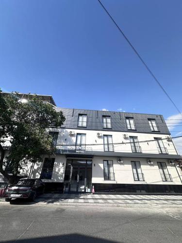 a white building with a car parked in front of it at North Star Hotel in Yakkasaray