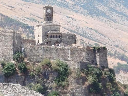 an old building with a clock tower on a mountain at RONDO Guesthouse in Gjirokastër