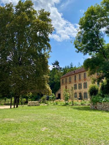 un vieux bâtiment en briques avec un arbre dans un champ dans l'établissement Maison as Cambous, à Sauveterre-la-Lémance