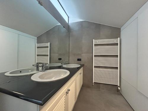 a bathroom with two sinks and two mirrors at Attico nel Centro di Novara in Novara