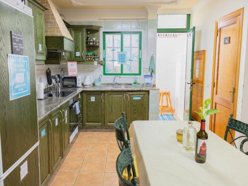 a kitchen with green cabinets and a table in it at Arena Nest Hostel in Puerto de Santiago