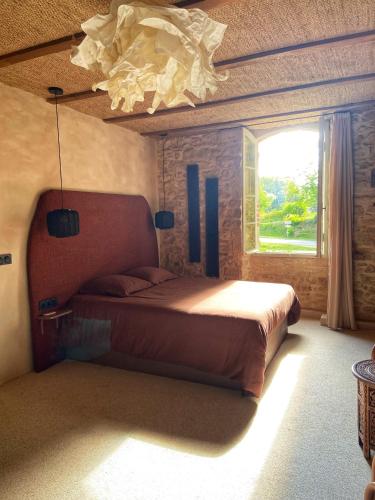 - une chambre avec un lit, une fenêtre et un lustre dans l'établissement Maison as Cambous, à Sauveterre-la-Lémance