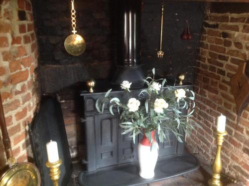 a fireplace with a vase of flowers and candles at The Greyhound - Historic former Inn in Glemsford