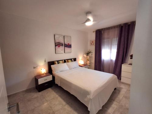 una camera da letto con un letto bianco e una finestra di Apartamento Tropicana a Denia
