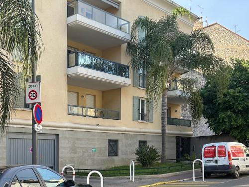un bâtiment avec un palmier devant dans l'établissement Appartement 2 Pièces Rénové avec Terrasse et Garage, à Cannes