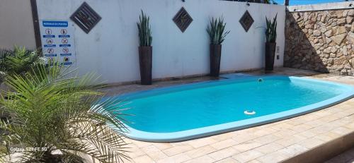 a blue swimming pool on a patio with plants at Pousada Bon Vivant in Cabo Frio