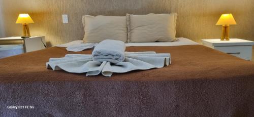 a bed with a towel on it with two lamps at Pousada Bon Vivant in Cabo Frio