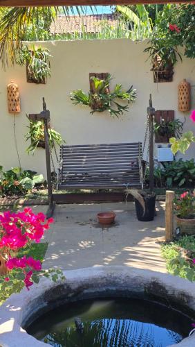 a garden with a bench and flowers and a pond at Pousada Bon Vivant in Cabo Frio