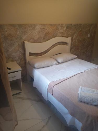 a bedroom with two beds and a side table at Pousada Bon Vivant in Cabo Frio