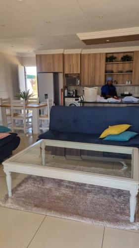 a living room with a blue couch and a kitchen at Lanseria FlyCom 