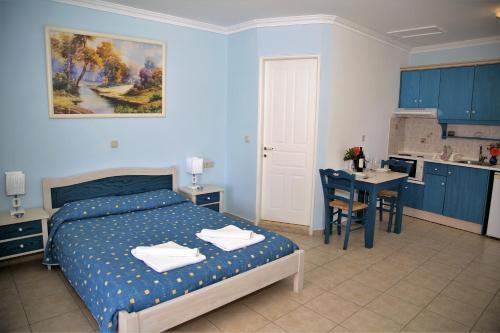 a bedroom with a bed and a table and a kitchen at Helen Apartments & Studios in Agios Stefanos