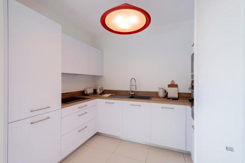 une cuisine avec des armoires blanches et un meuble lumineux dans l'établissement Spacious 4BR with Lovely Balcony, à Bordeaux