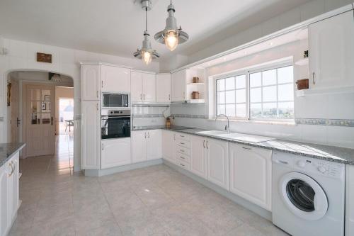 a kitchen with white cabinets and a washer and dryer at Casa Casimiro mit privaten beheizten Pool in Pêra
