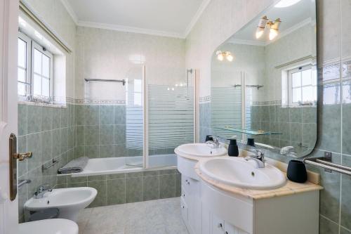a bathroom with two sinks and a mirror and a tub at Casa Casimiro mit privaten beheizten Pool in Pêra