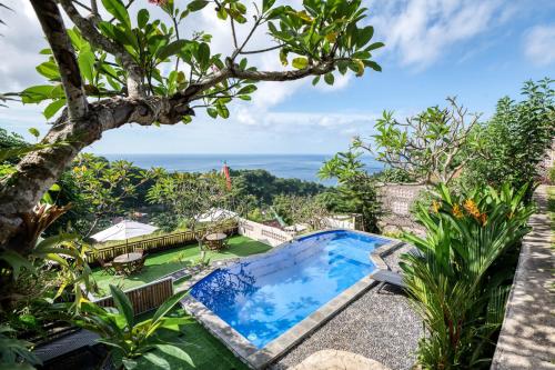 a pool in a garden with a view of the ocean at Adinata Villa by Manara in Seraya