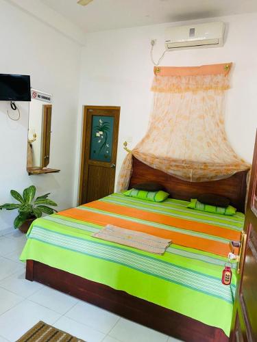 a bedroom with a bed with a colorful bedspread at Dinimuthu Rest Inn in Wellawaya