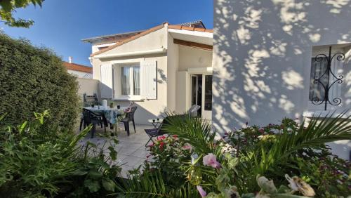 Cette maison dispose d'une terrasse avec une table et des fleurs. dans l'établissement Saint Georges de Didonne - PETITE MAISON avec son petit coin de paradis extérieur, à Saint-Georges-de-Didonne