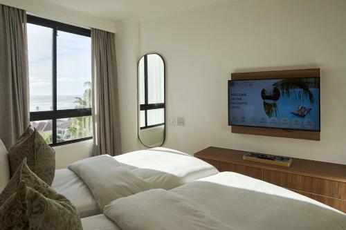 a hotel room with two beds and a flat screen tv at President Hotel in Cape Town