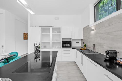 a kitchen with white cabinets and a black counter top at Luxury House Jacuzzi - Milano in Milan