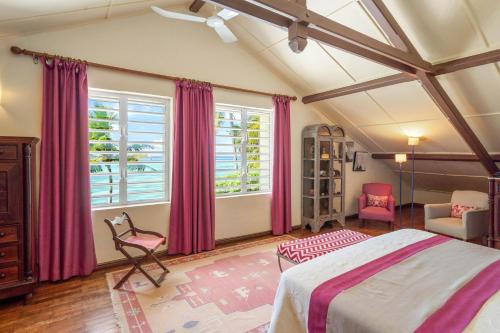 a bedroom with pink curtains and a bed and a chair at Villa du Bonheur, maison de luxe en bord de mer by IHR in Roches Noires