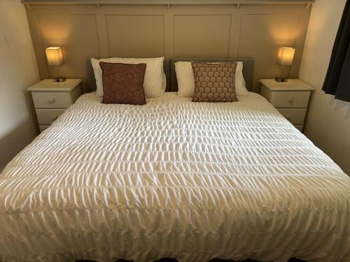 a large white bed with two nightstands and two lamps at Rooms at the Inn in Trotton