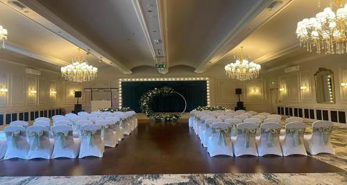 a room with rows of tables and chairs with chandeliers at Roker Hotel BW Premier Collection in Sunderland