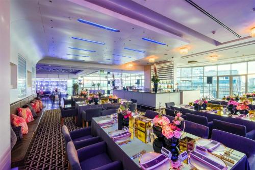 a restaurant with purple chairs and tables and flowers at Radisson Blu Gautrain Hotel, Sandton Johannesburg in Johannesburg