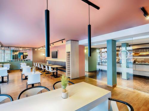a restaurant with white tables and chairs and a cafeteria at B&B Hotel Bremen-City in Bremen