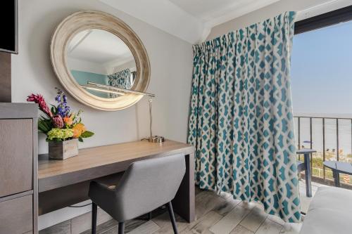 einen Schreibtisch in einem Zimmer mit einem Spiegel und einem Fenster in der Unterkunft Crystal Coast Oceanfront Hotel in Pine Knoll Shores