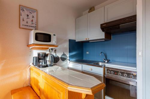 une petite cuisine avec un évier et un micro-ondes dans l'établissement Charming studio at the foot of the ice rink, au Grand-Bornand