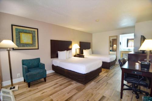 a hotel room with two beds and a desk and a chair at Hotel SonoHotel IDrive District in Orlando