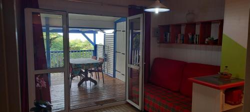a living room with a sliding glass door to a deck at Le Colibri, belle vue mer, accés direct à la plage, SPA privatif in Bouillante