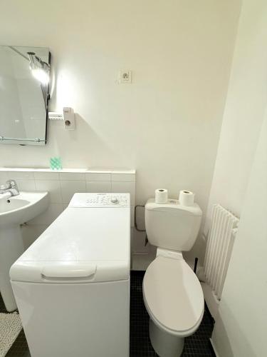 Un baño blanco con inodoro y lavabo. en Appartement Brochant Batignolles Paris, en París