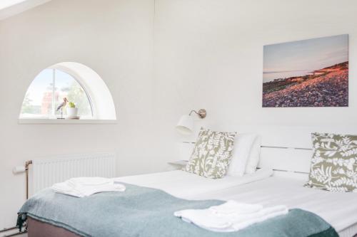 a white bedroom with a bed with a window at Röda Magasinet in Mariefred