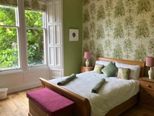 a bedroom with a bed with green walls and windows at Victorian Apartment with car parking in driveway, Murrayfield in Edinburgh