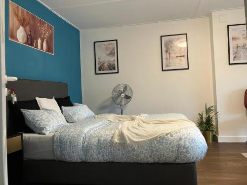 a bedroom with a bed with blue walls and a fan at Gaby's House in Liège