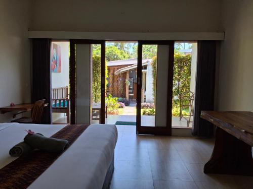 - une chambre avec un lit et des portes coulissantes en verre dans l'établissement Sammy Cottage Senggigi, à Mangsit
