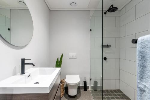 Un baño con lavabo, inodoro y ducha. en 1-Bedroom Ocean-View Apartment Wavescapes, Muizenberg Beach, en Muizenberg