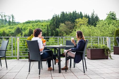two women sitting at a table with a cup of coffee at Spa & Wellness Vila Antoaneta in Lázně Luhačovice