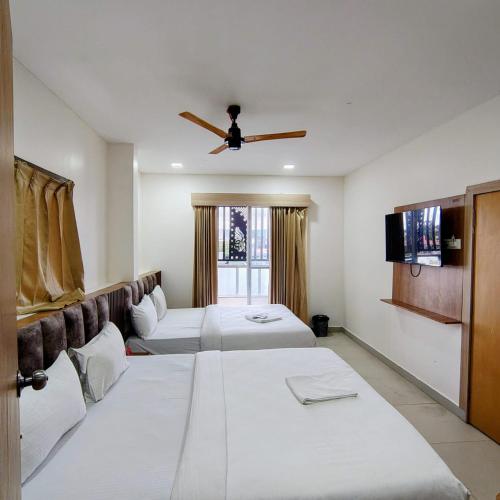 a hotel room with two beds and a ceiling fan at Hotel RK Koramangala in Bangalore